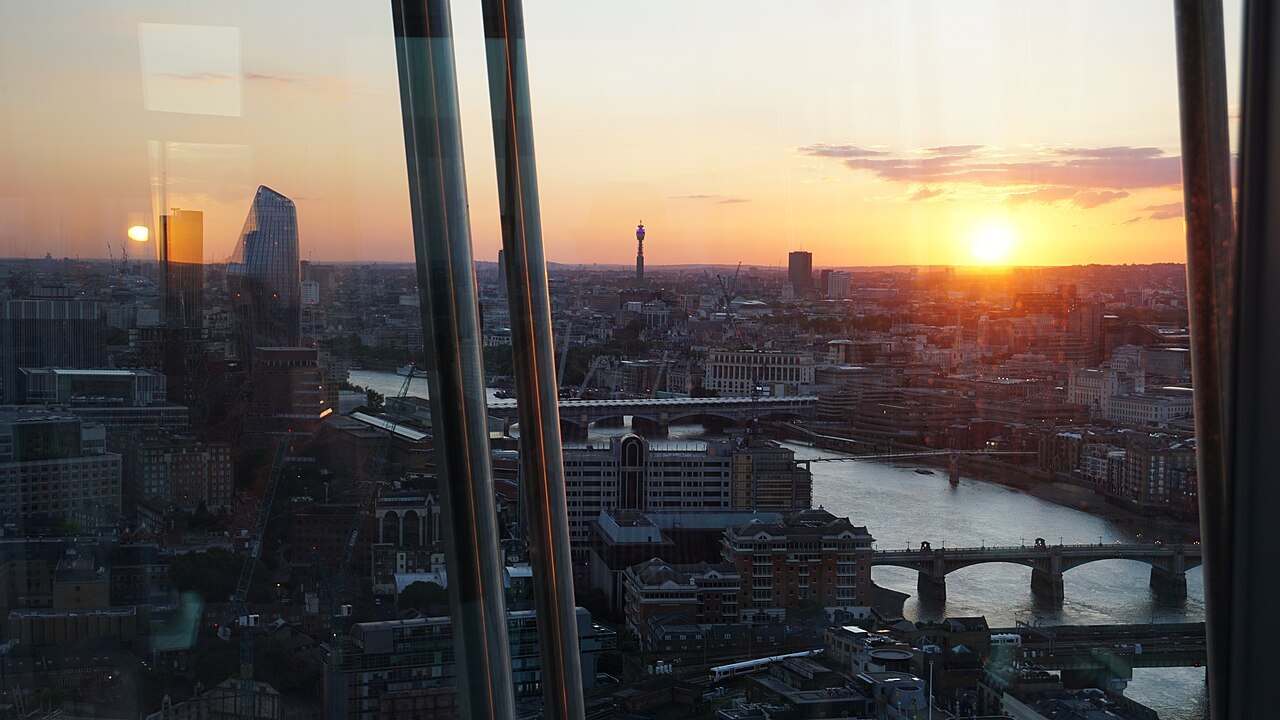 The sun setting over the City from a high window, with the Thames and its bridges below