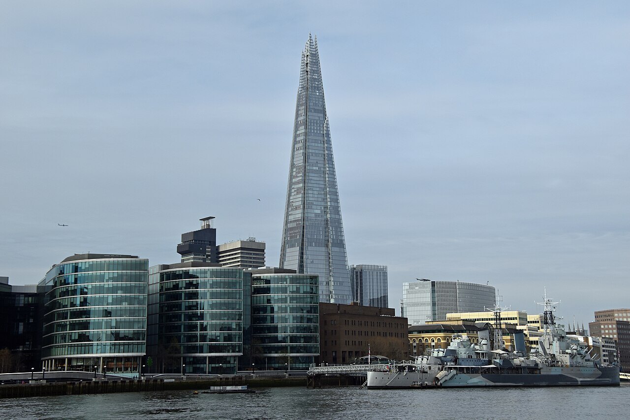 The Shard and the glass offices at Southwark, with a warship moored on the river