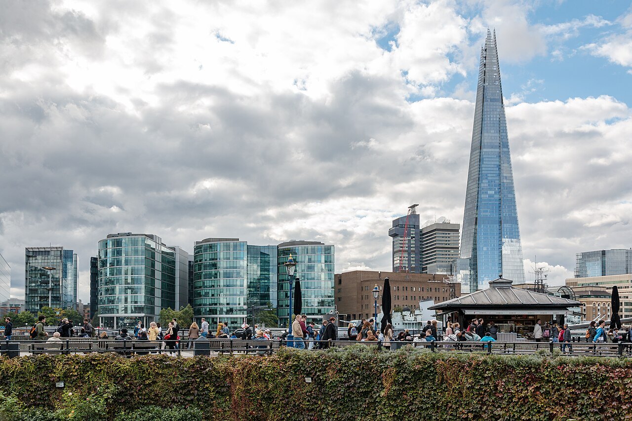 The Shard above the glass offices and riverside terrace at Southwark, with people along the wall