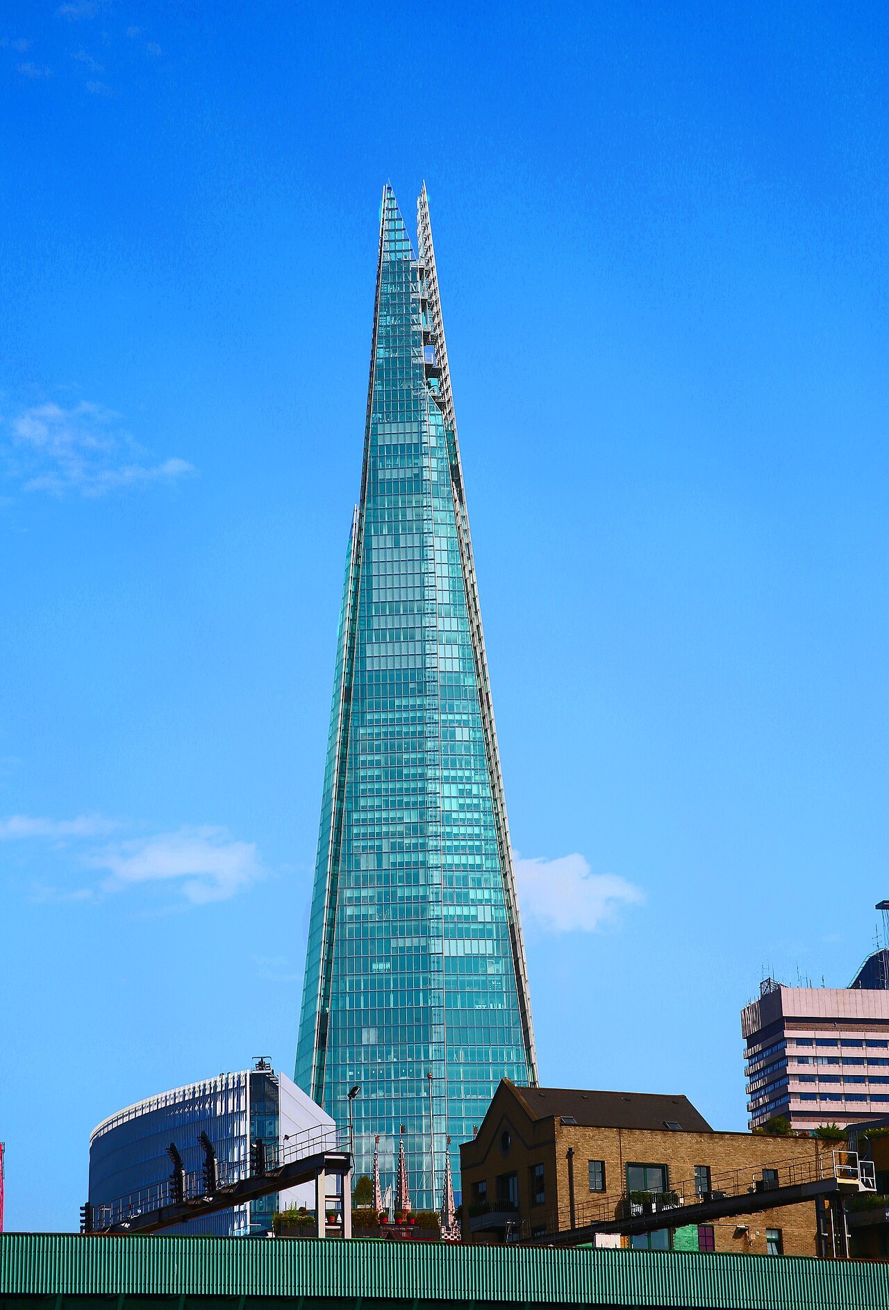 The glass spire of the Shard shot from the street against deep blue sky
