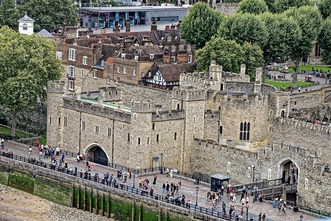 The Tower of London's outer wall and gate with its moat, seen from above with visitors on the path