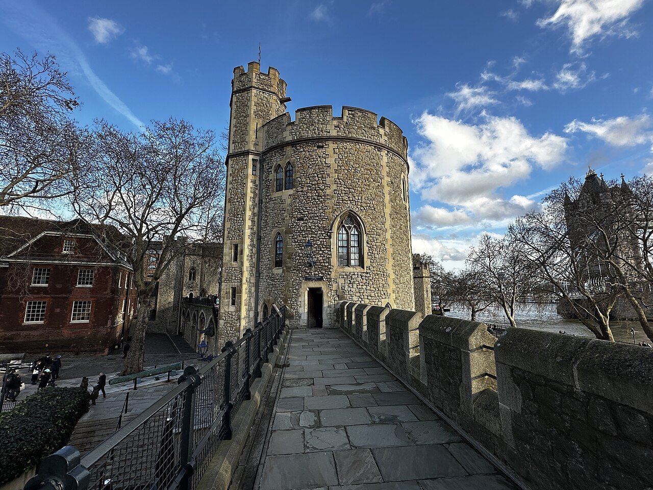 The Lanthorn Tower on the Wall Walk, a round stone tower beside a paved path with Tower Bridge at the right