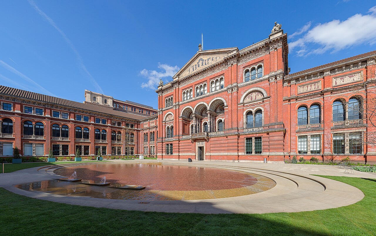 The V&A's central garden, a lawn and a shallow round pool in front of the museum's red brick buildings