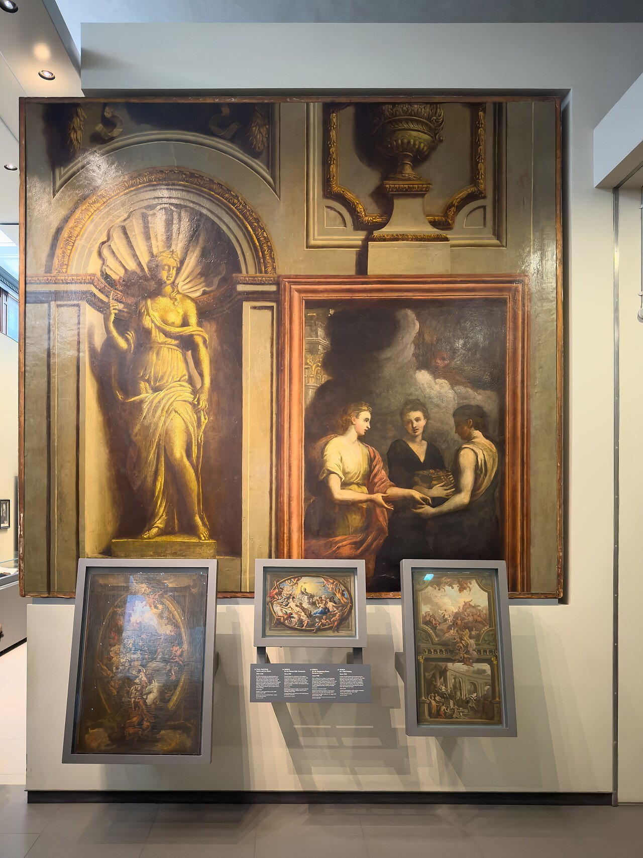 An alcove in a V&A gallery hung with old paintings and a small group of objects in a case